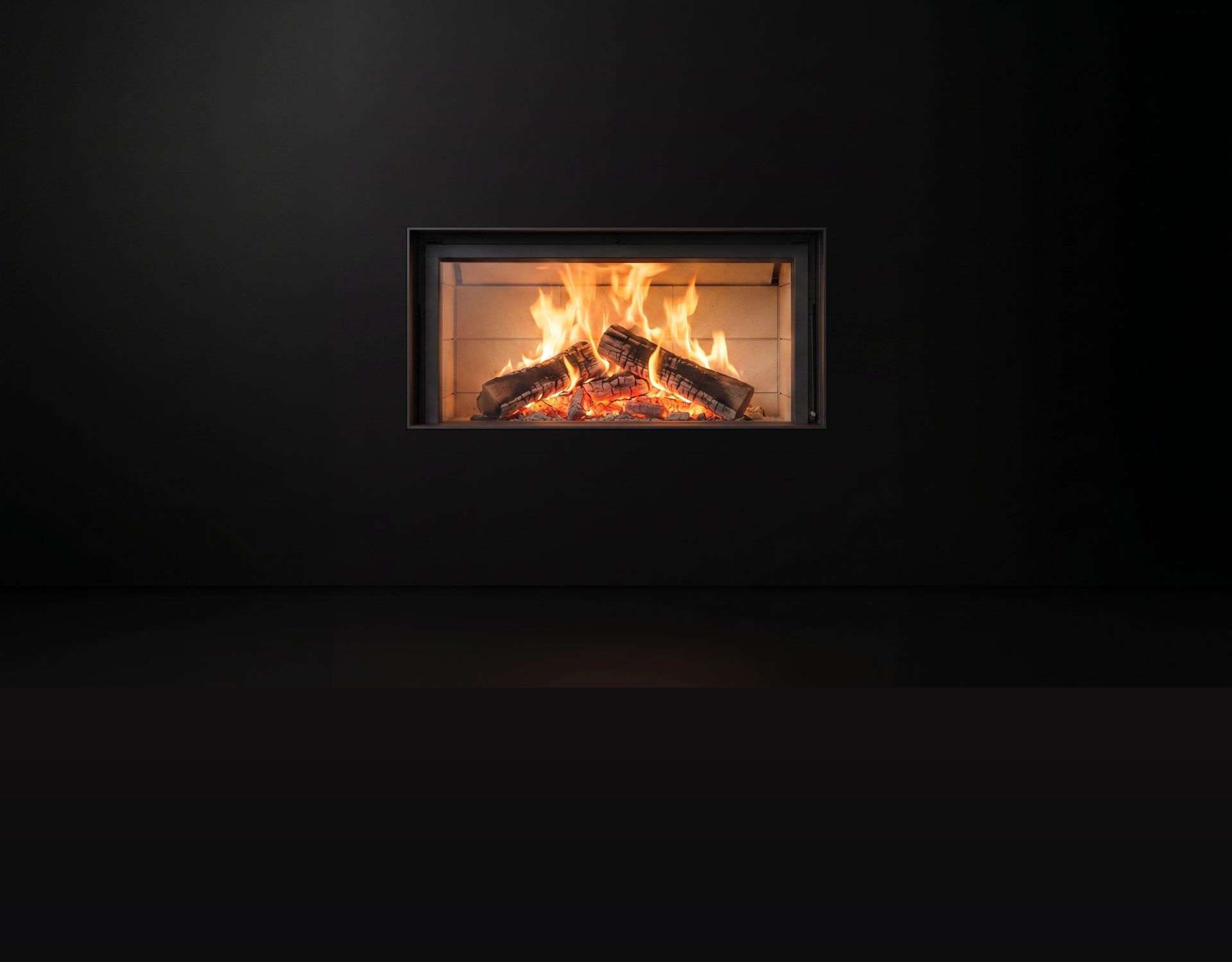 A Stûv wood fireplace burning behind glass, photographed alone on black
