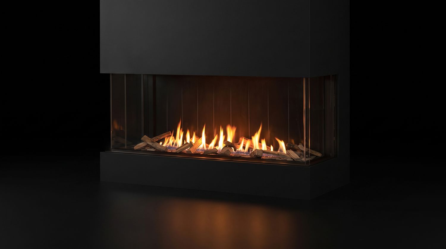 An Urbana U70 Tall Bay gas fireplace burning on three glass sides, photographed on black