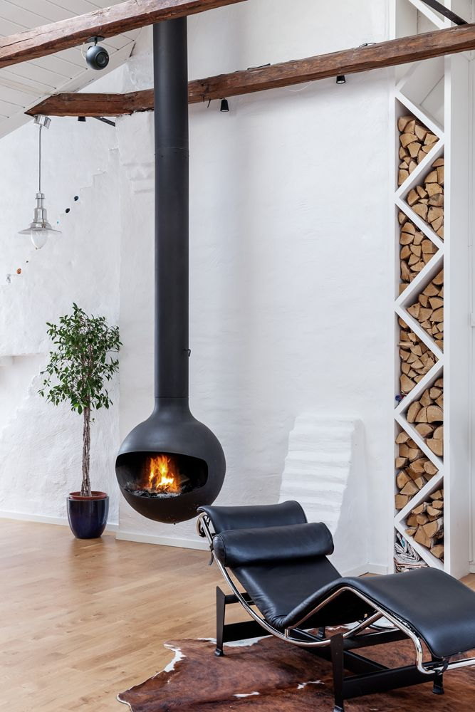 Black Bathyscafocus in a whitewashed loft beside a tall stacked woodpile and leather chaise