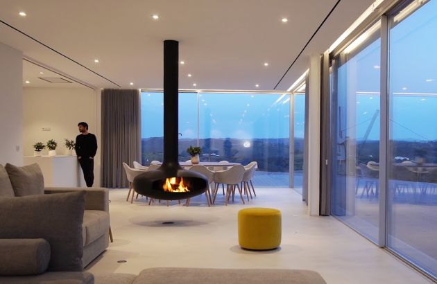 Domofocus burning at dusk in a glazed living room overlooking the water