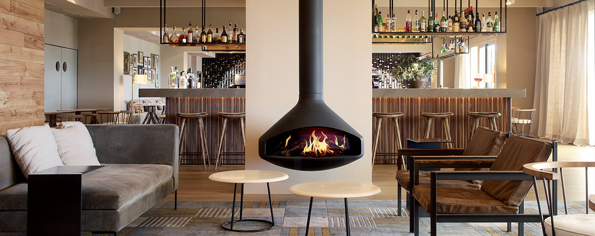 Ergofocus Holographik electric fireplace glowing behind a restaurant bar, its holographic flame lit