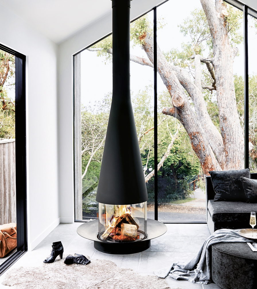 Filiofocus Central burning beside floor-to-ceiling glass under an old tree