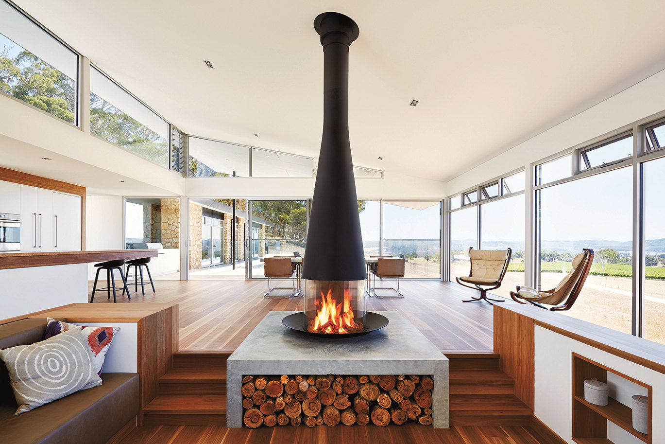 Filiofocus 2000 hanging over a stone hearth plinth stacked with logs in a glass beach house
