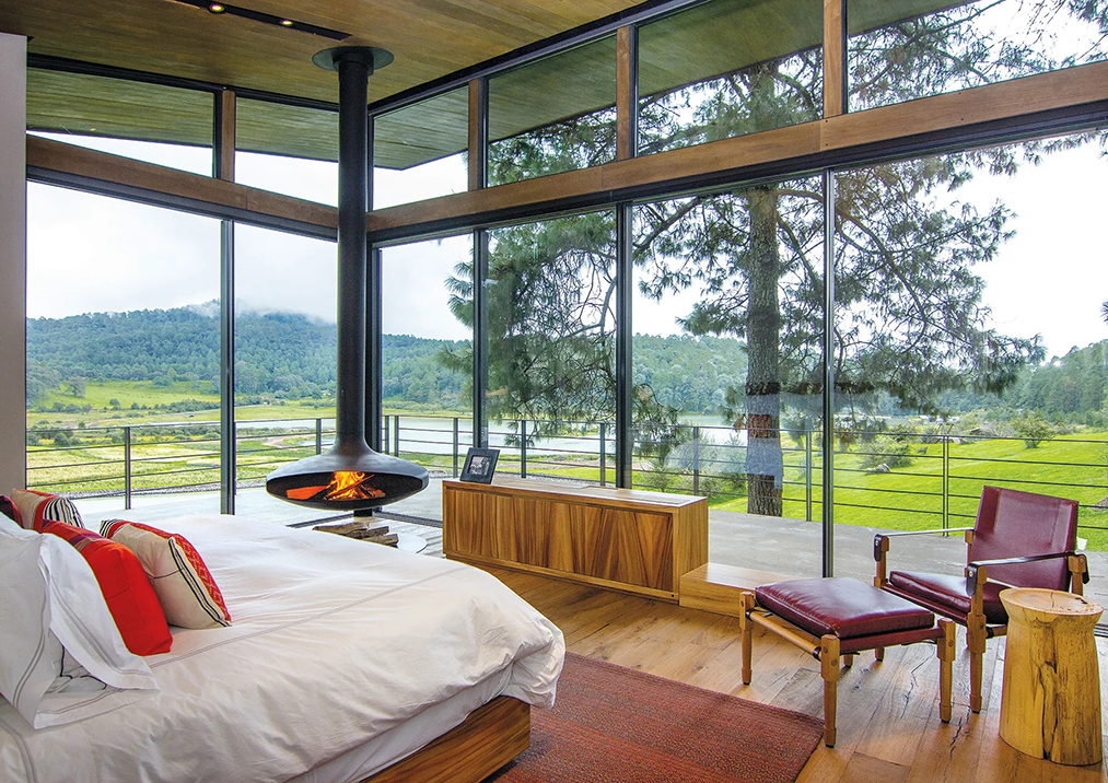 Gyrofocus hanging in a timber bedroom, its open fire turned toward the bed, a green valley beyond the glass