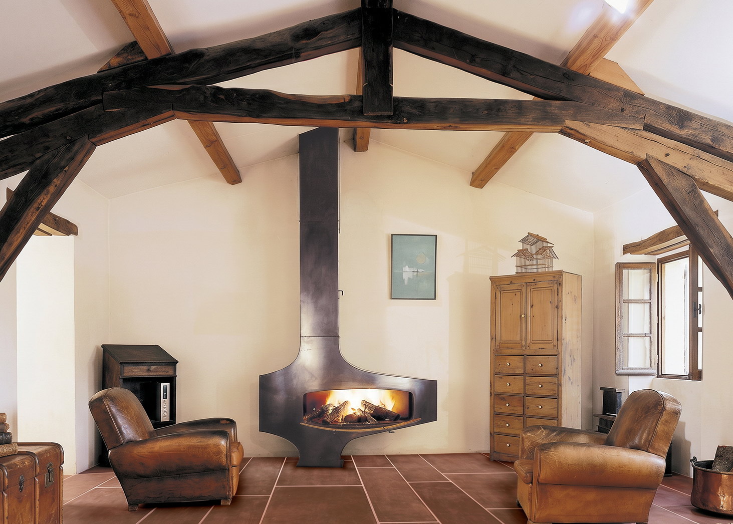 Heterofocus alight against a white wall under dark timber trusses, leather armchairs on a terracotta tile floor