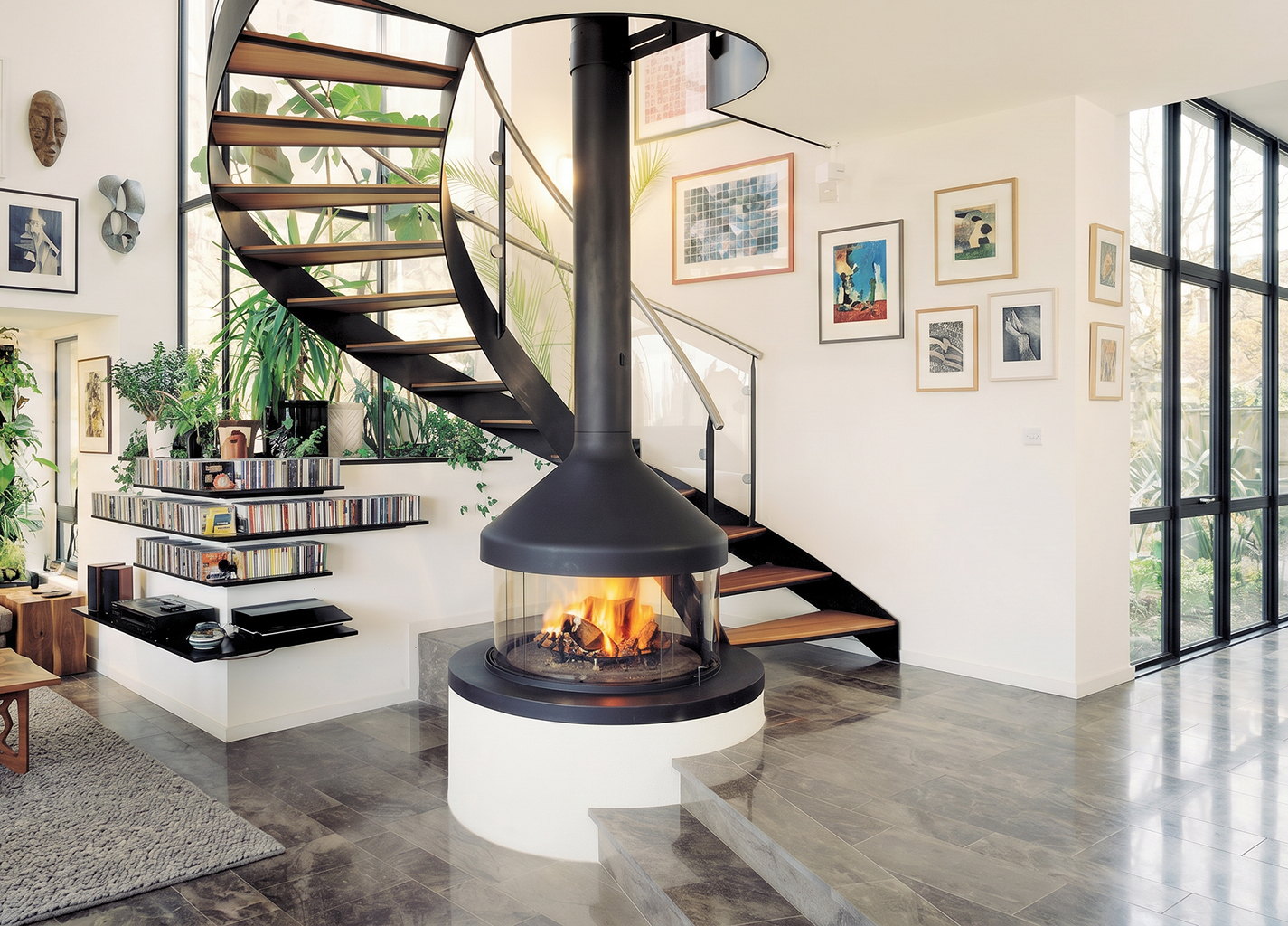 Meijifocus wood burning on a white plinth beneath a spiral staircase and a wall of pictures