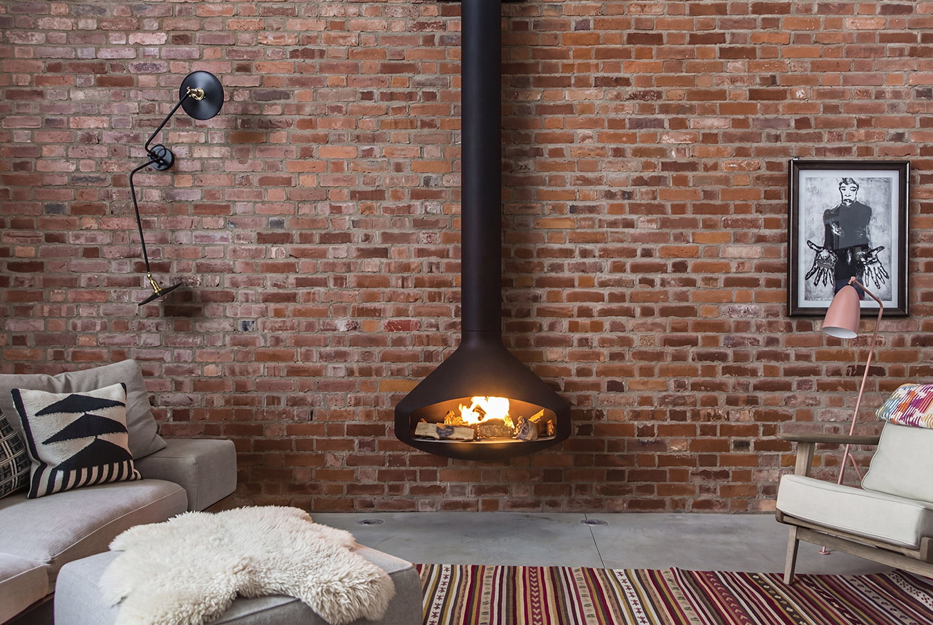 Paxfocus gas burning against an exposed brick wall above a sheepskin and a kilim rug