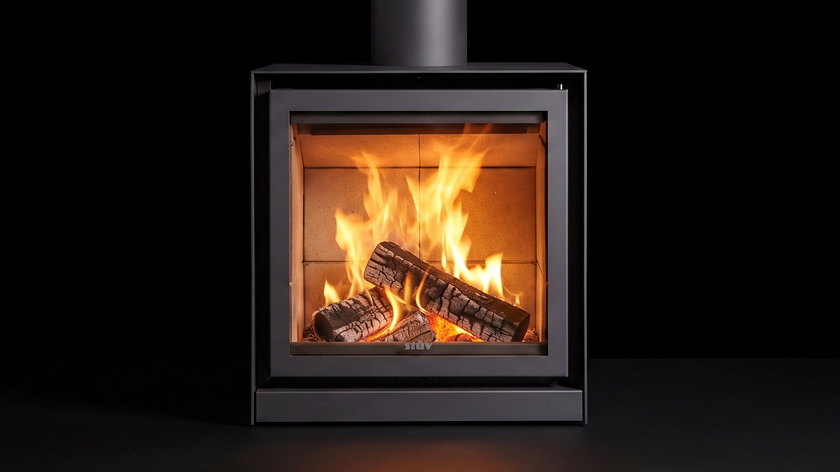 The Stûv 16 Cube — wood stove — burning in the black studio void