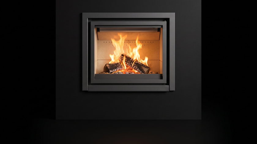 The Stûv 16-in — wood-burning insert — burning in the black studio void