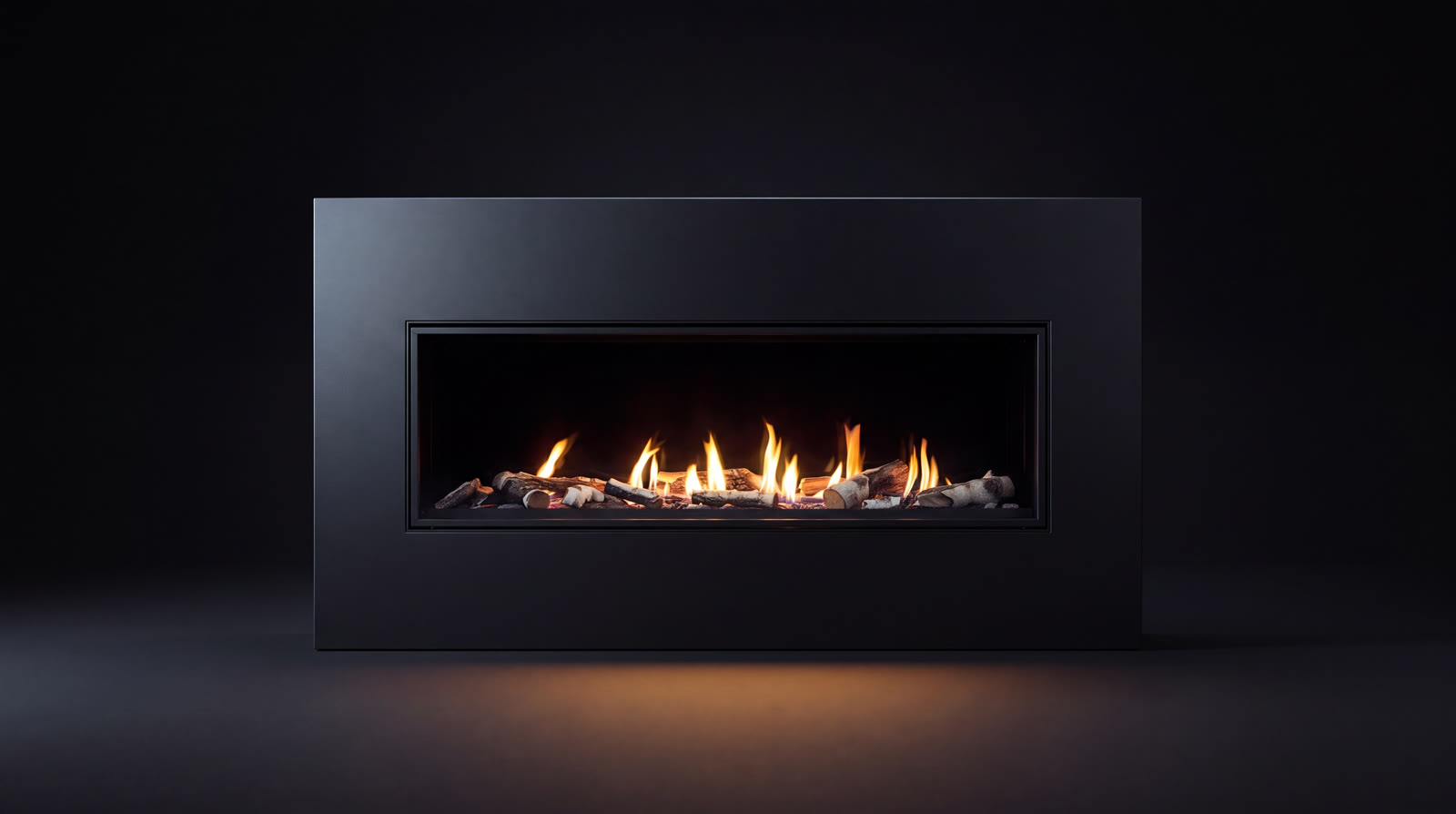 An Enviro gas fireplace, a wide ribbon of flame over driftwood logs in a matte black surround
