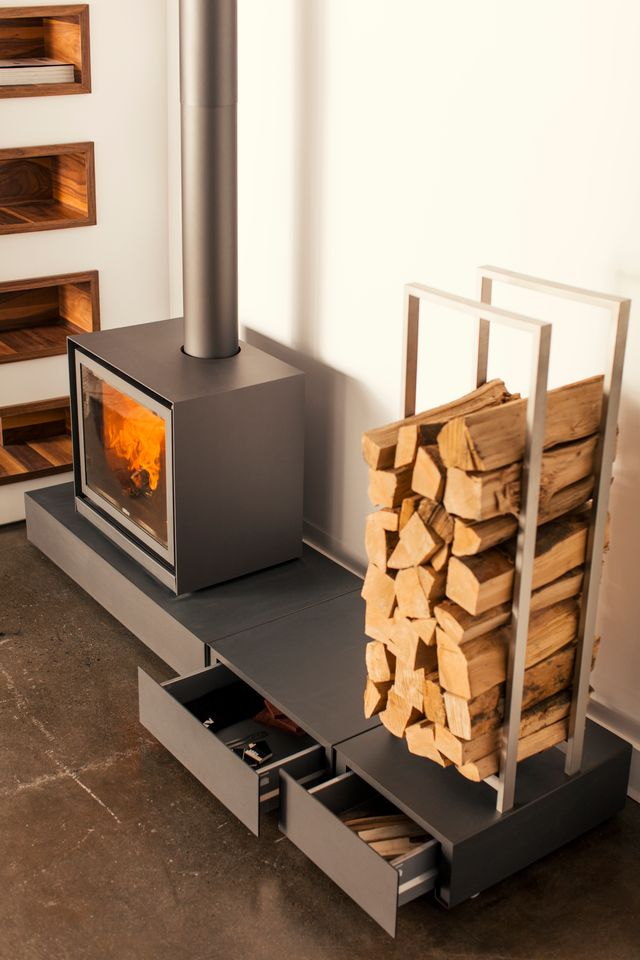 The Stûv 16-cube on its storage bench — firewood drawers below, log rack beside