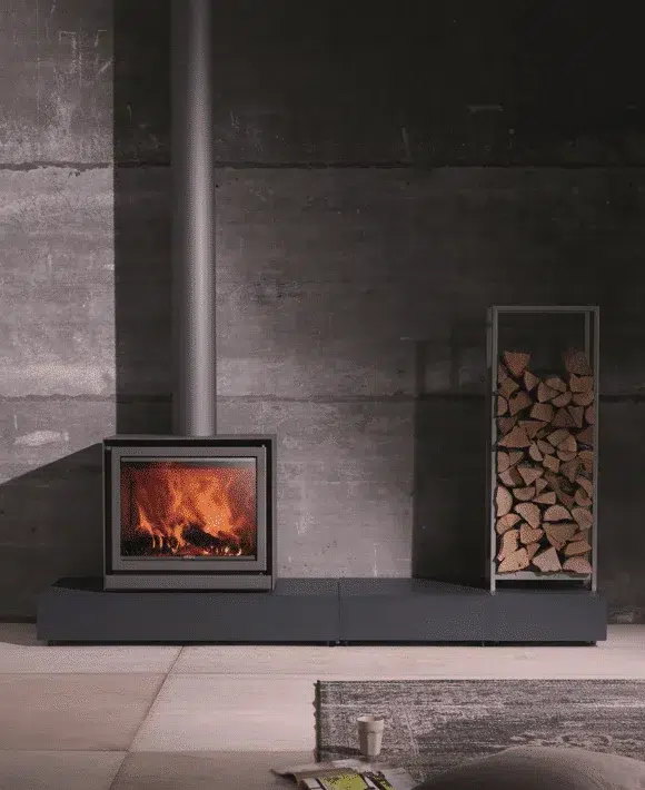The Stûv 16-cube on a long low bench against raw concrete, a log tower beside