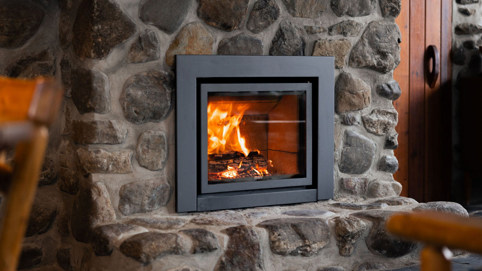 Stûv 16-in burning in the fieldstone chimney of a 1970s Eastern Townships house