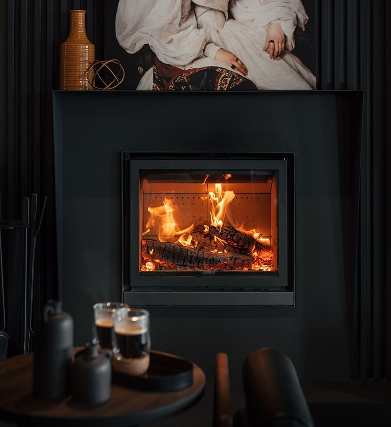 The Stûv 16-in blazing from a black panelled wall over a low coffee table