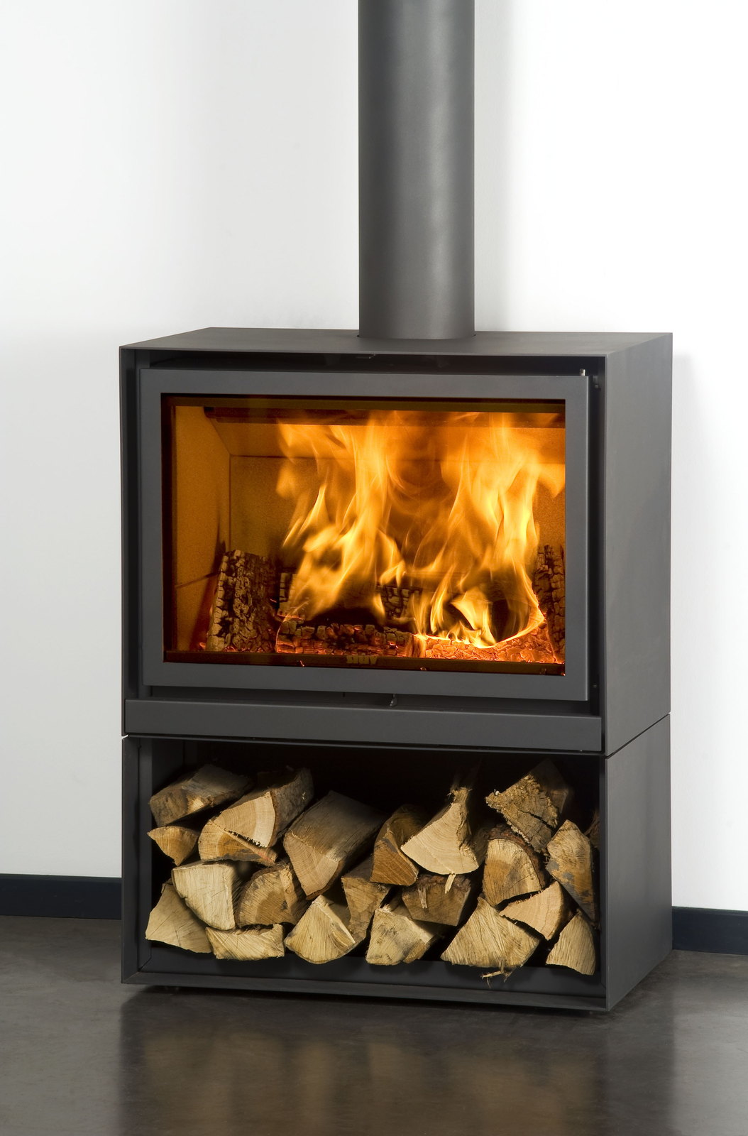 The Stûv 16-H head on, fire roaring above a full firewood base