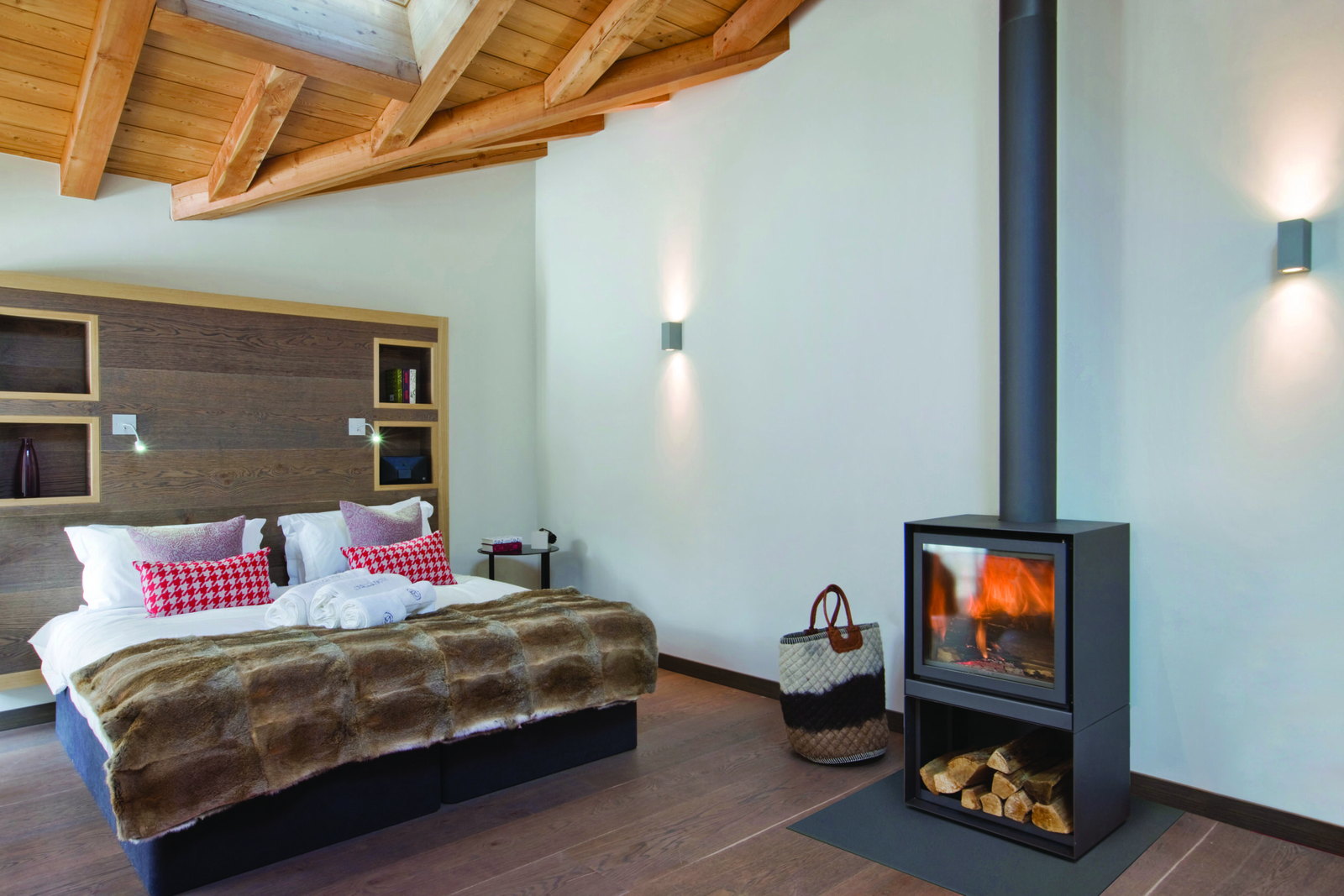 The Stûv 16-H burning at the foot of a bed beneath heavy timber beams