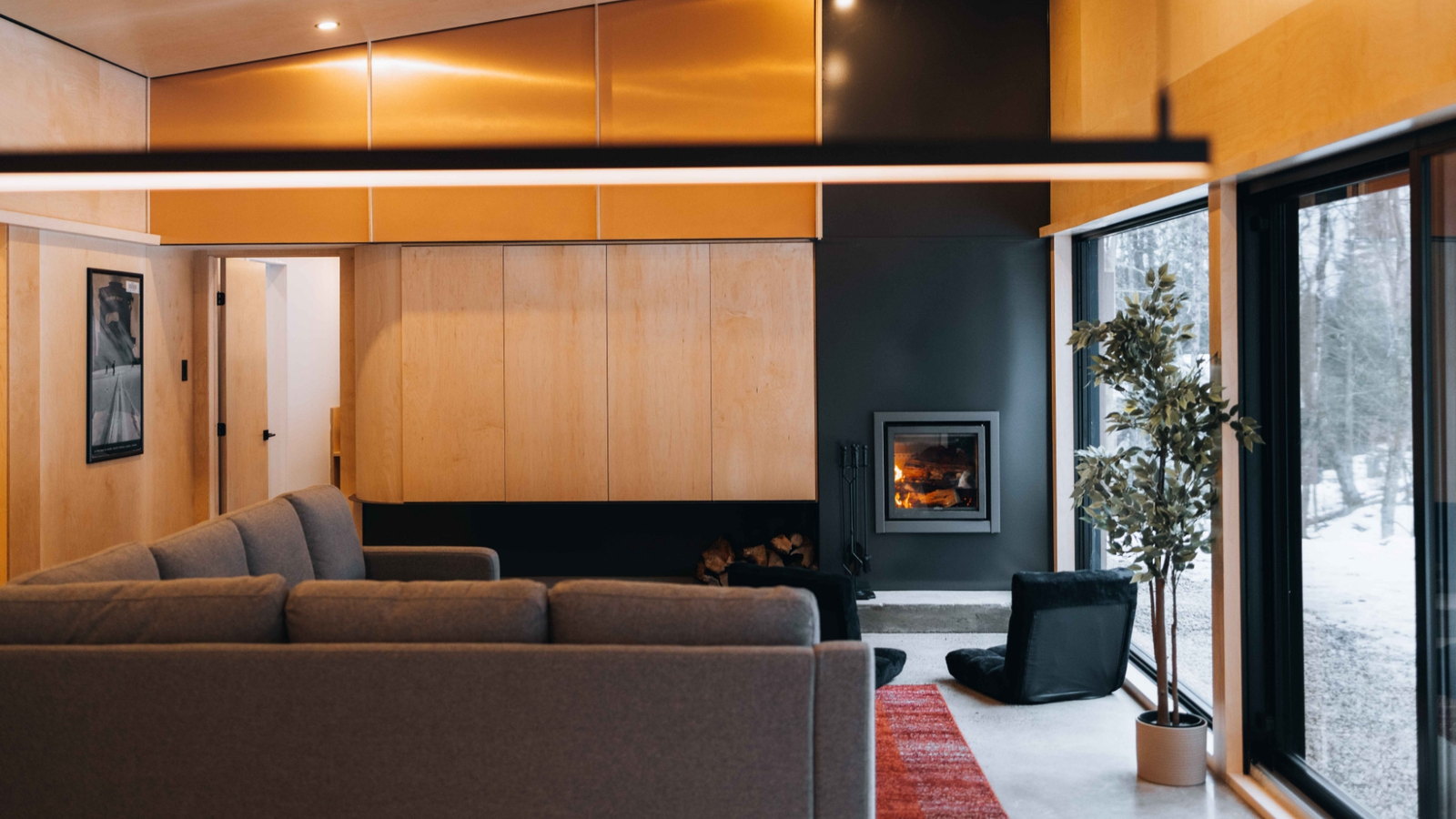Stûv 16-Z burning in a black fireplace wall between maple panelling and a snowy window