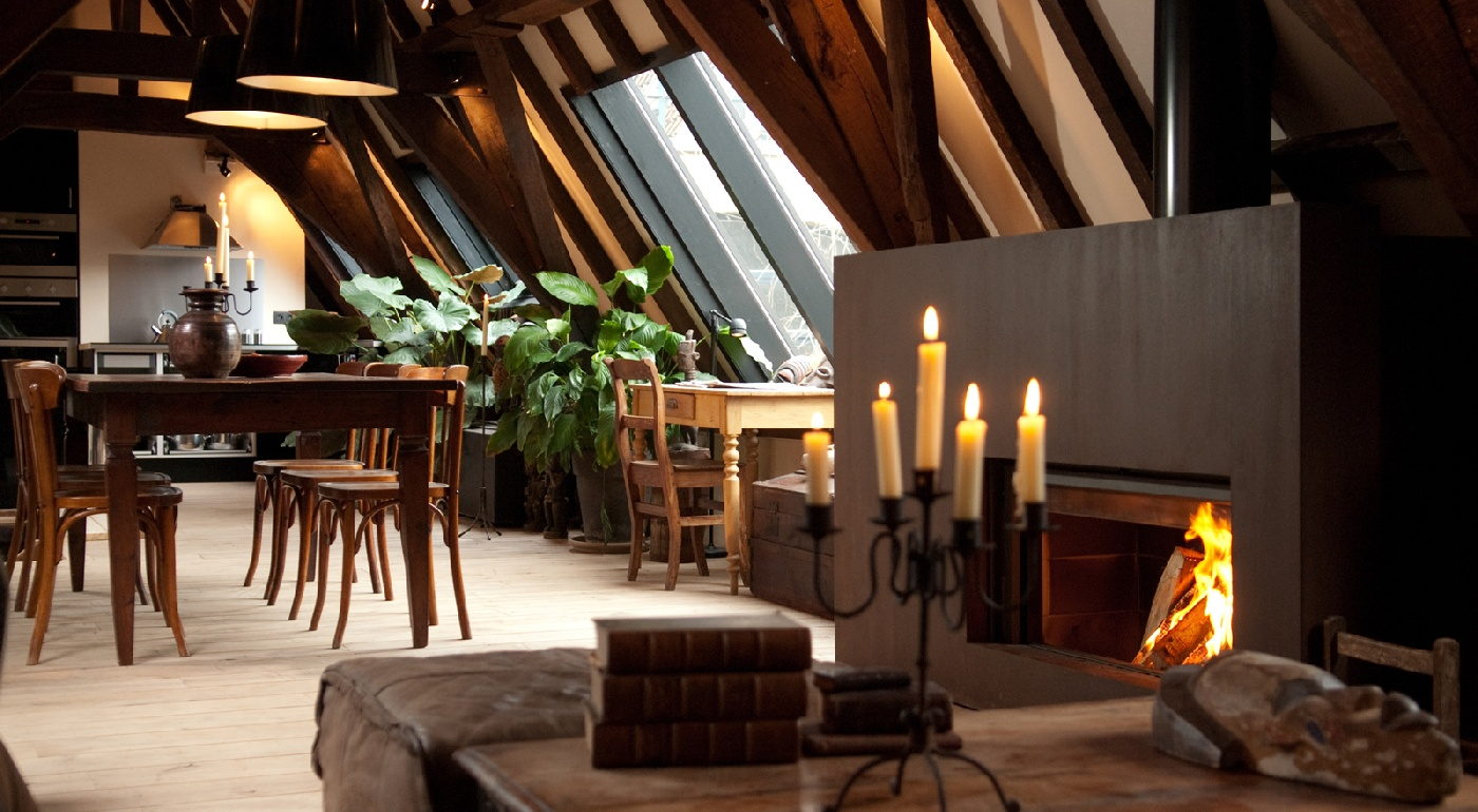 Stûv 21 ready-to-fit fireplace with its cladding, burning in a timber attic dining room