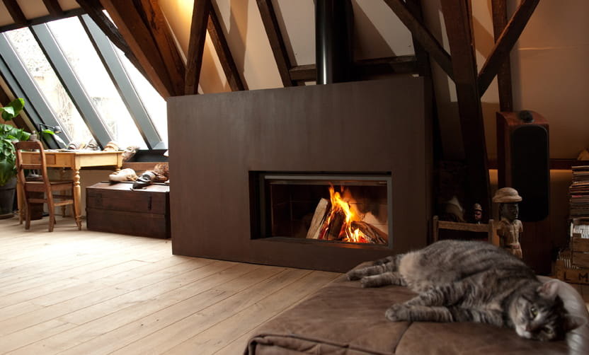 The rust Stûv 21-clad warming a timber attic, the house cat stretched out beside it
