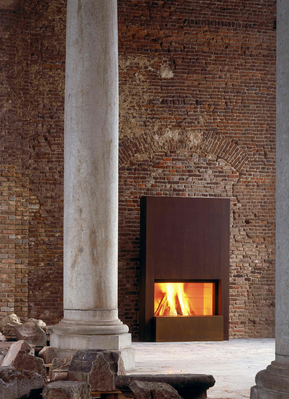 The Stûv 21-125 in a rust surround between brick and a marble column