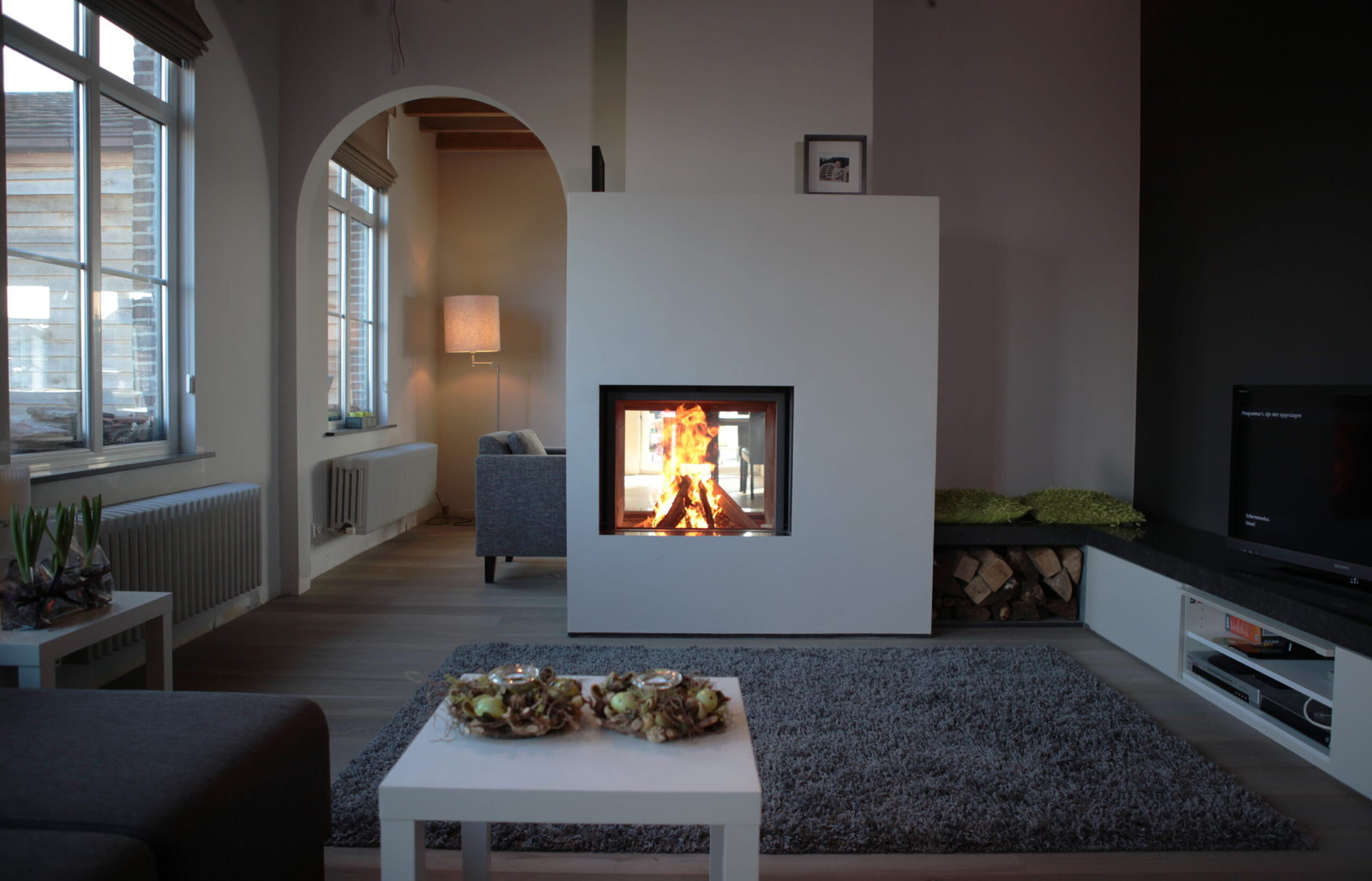 The Stûv 21 double-face burning through a white dividing wall between two rooms