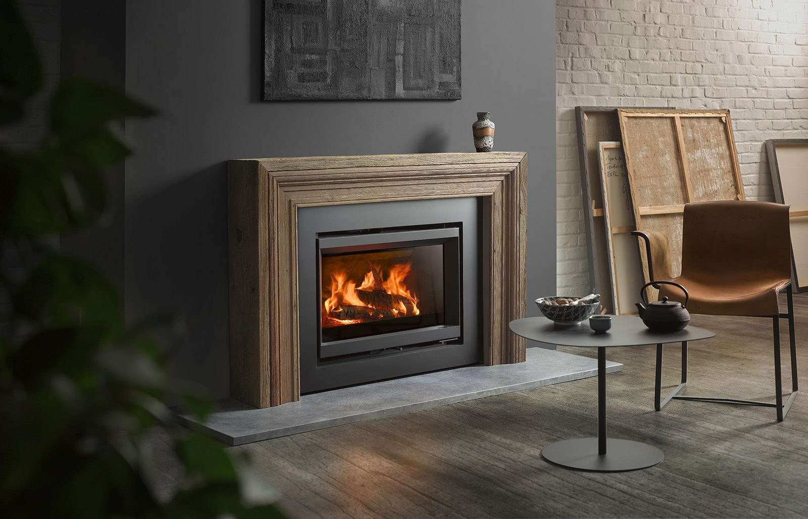 Stûv 6-in insert burning in a deep timber frame on a gallery wall