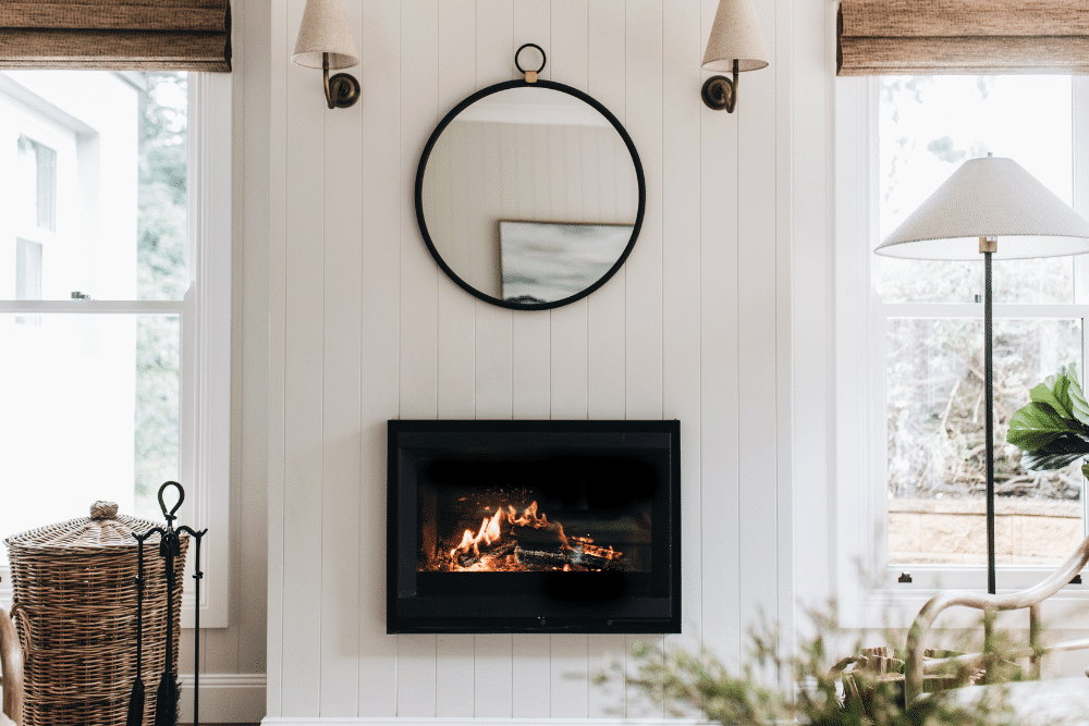 The Stûv 6-in burning in a white panelled wall beneath a round mirror
