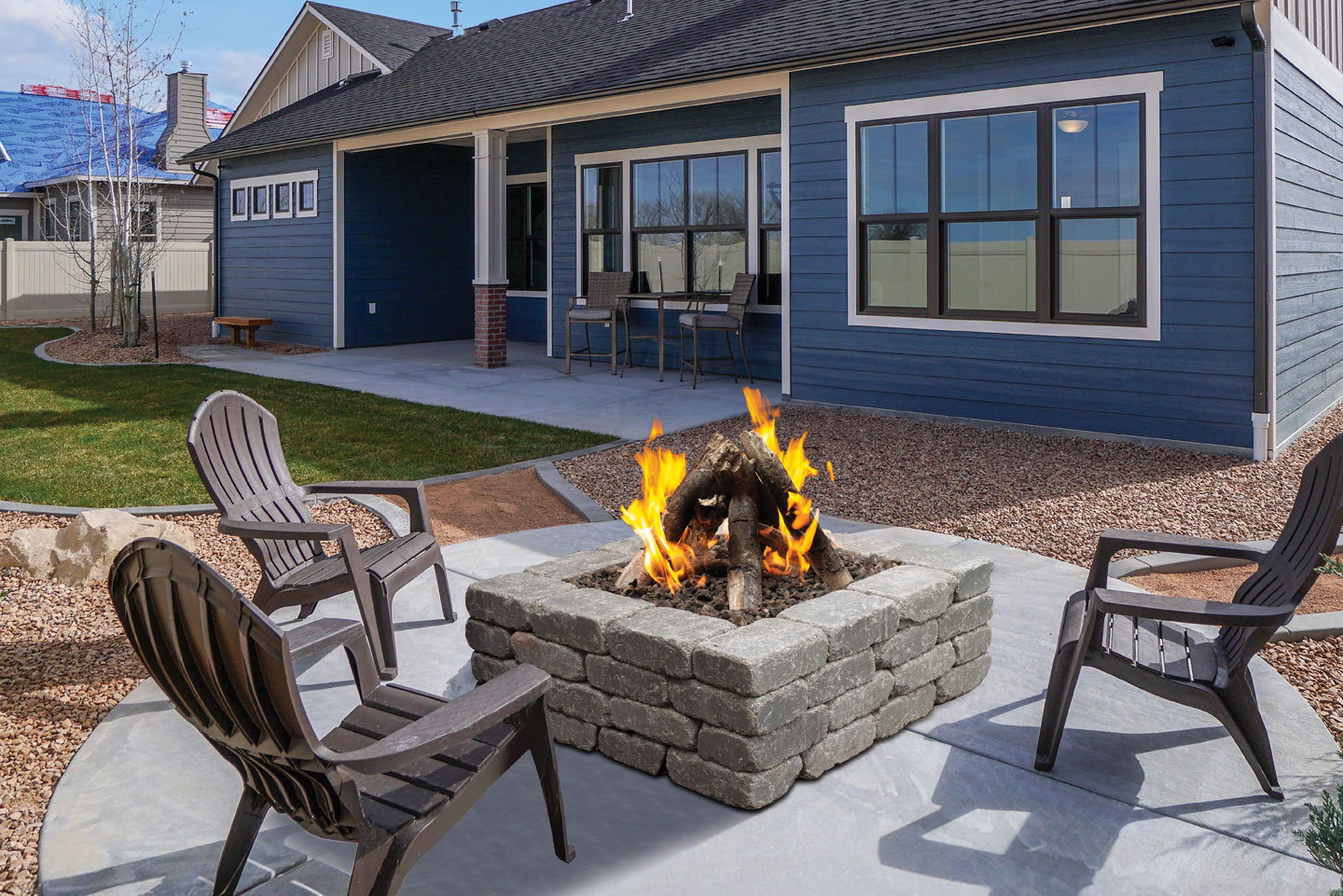 Halo brick fire pit burning on a backyard patio with adirondack chairs