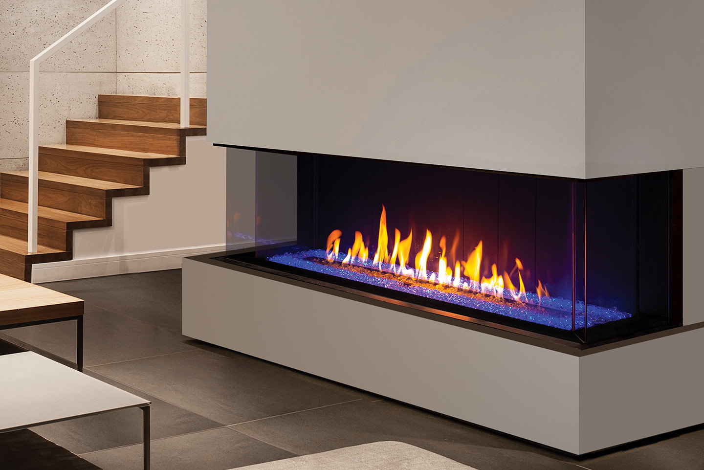 Urbana U70 Bay three-sided gas fireplace on a white plinth beneath a staircase