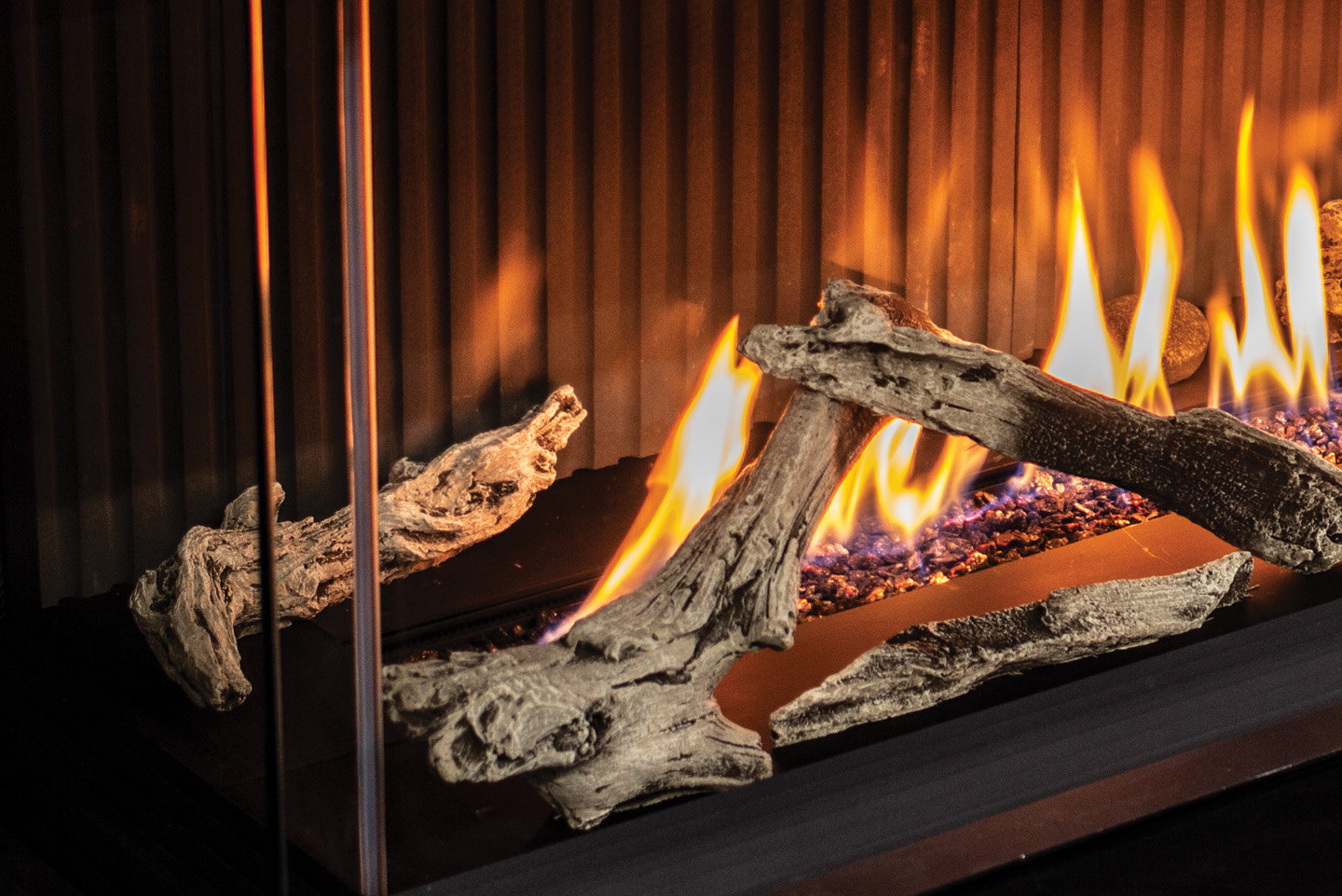Driftwood logs burning in the corner glass of the Urbana U70 Bay