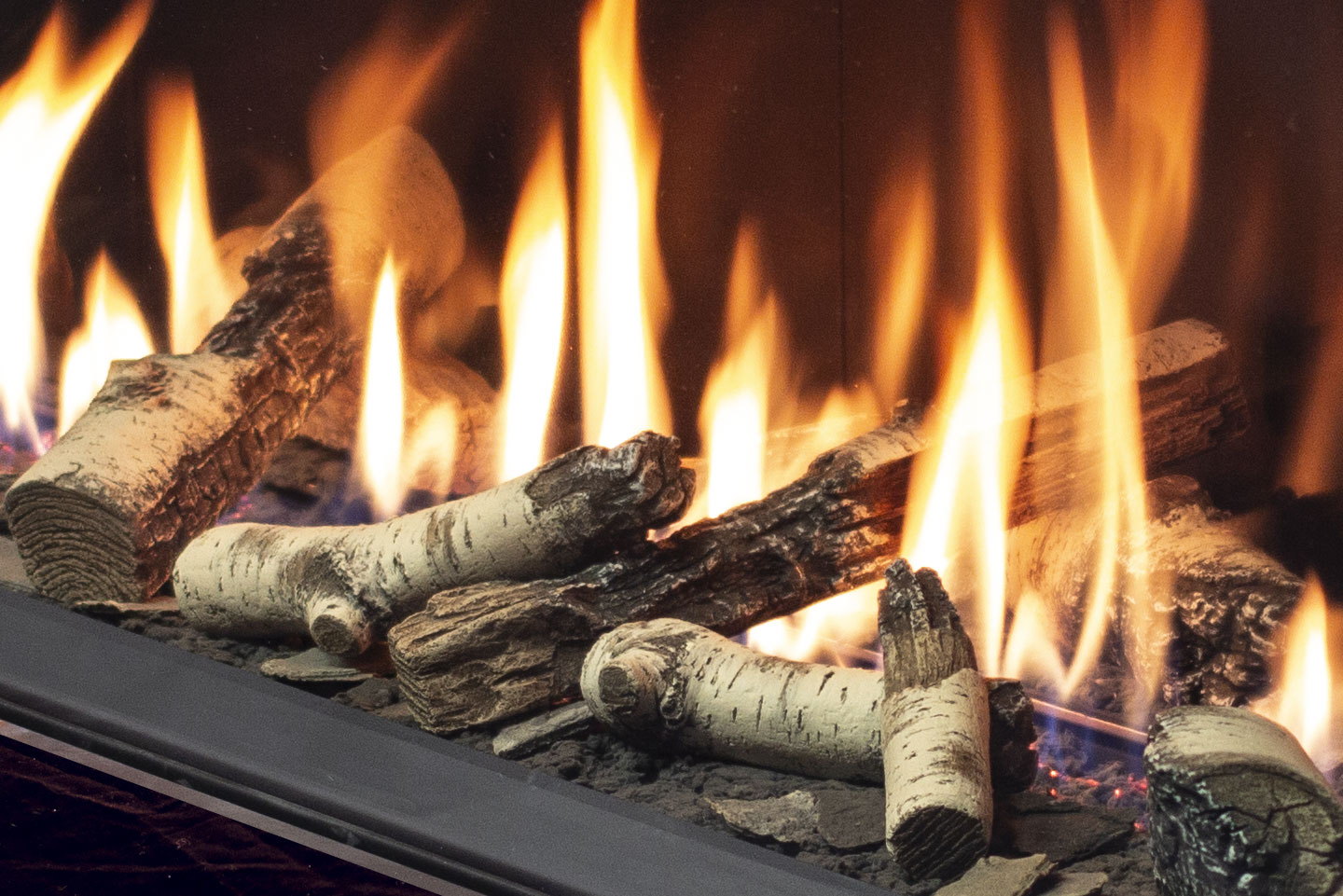 Birch logs burning behind the tall glass of the Urbana U70 Tall Linear